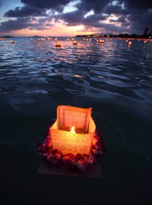 Honolulu, Hawaii: A lantern draped with a flower lei floats on the water